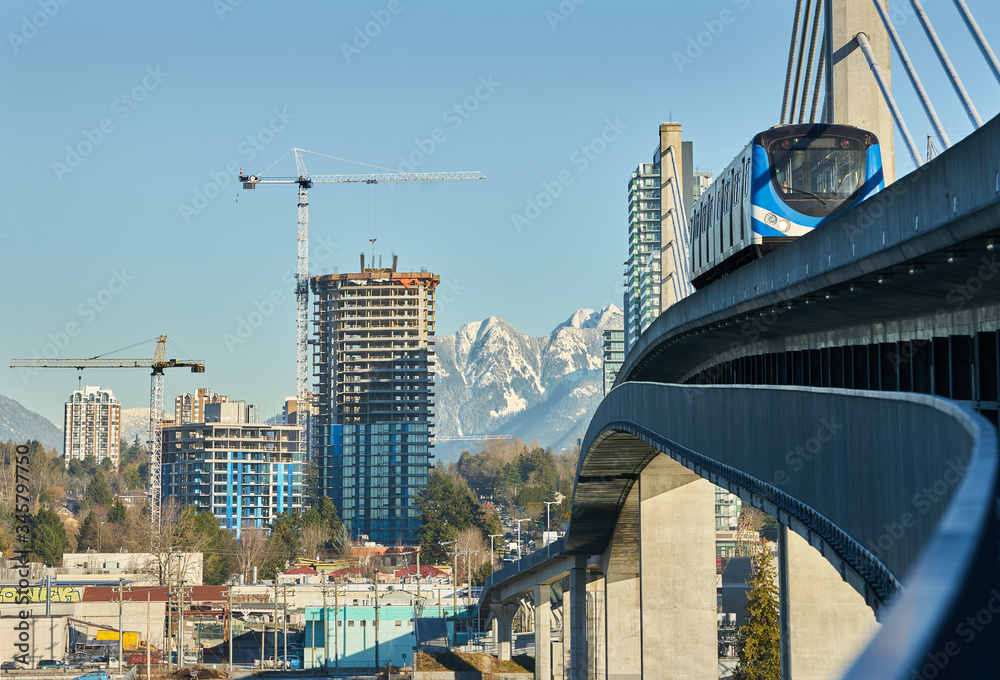 Obraz premium Urban Growth Vancouver. Modern towers grow along Vancouver’s skyline behind a rapid transit line. British Columbia, Canada.