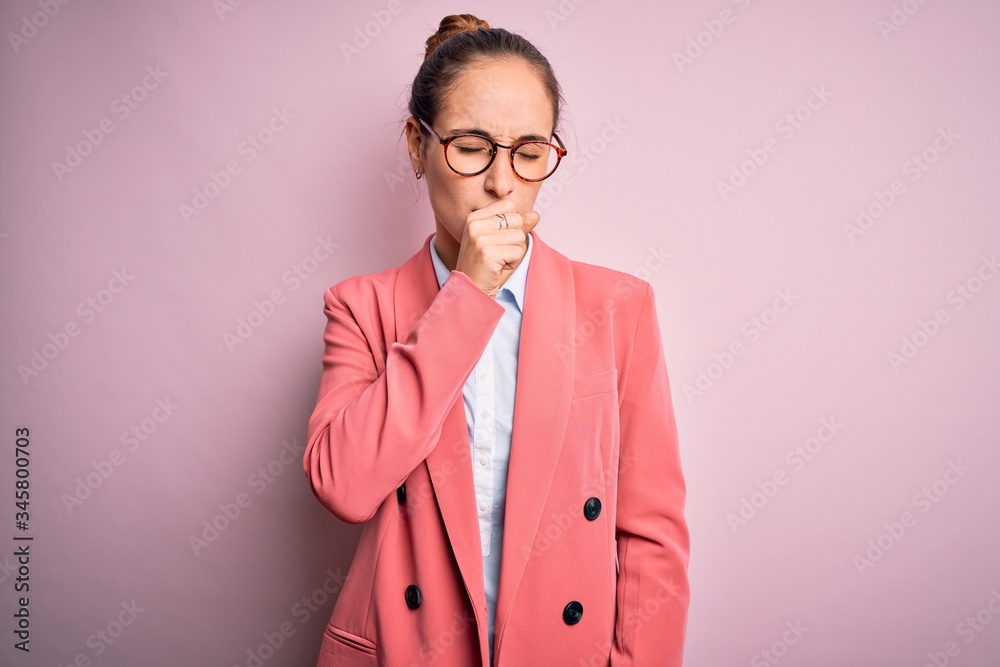 Young beautiful businesswoman wearing jacket and glasses over isolated pink background feeling unwell and coughing as symptom for cold or bronchitis. Health care concept. Young beautiful businesswoman wearing jacket and glasses over isolated pink background feeling unwell and coughing as symptom for cold or bronchitis. Health care concept.