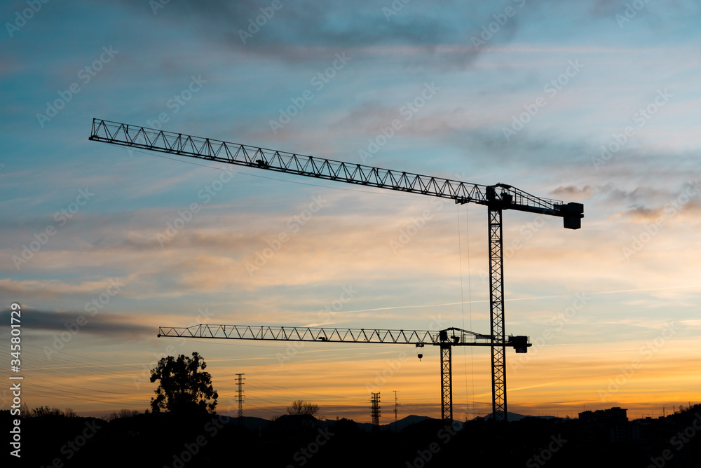Silhouettes of tower cranes against the night sky House under construction. Industrial corner Silhouettes of tower cranes against the night sky House under construction. Industrial corner