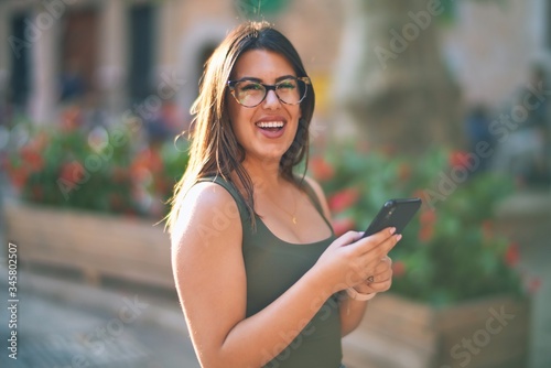 Young beautiful woman smiling happy and confident. Standing with smile on face using smartphone at the city