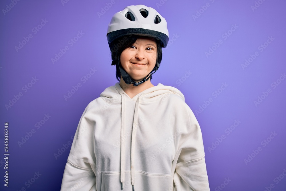 Young down syndrome cyclist woman wearing security bike helmet over purple  background with a happy and cool smile on face. Lucky person. Stock Photo |  Adobe Stock
