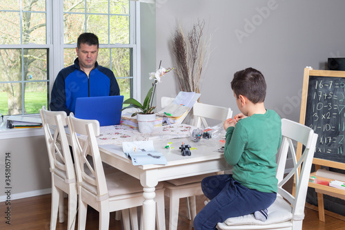 Father working from home while his child is playing in the dining  table