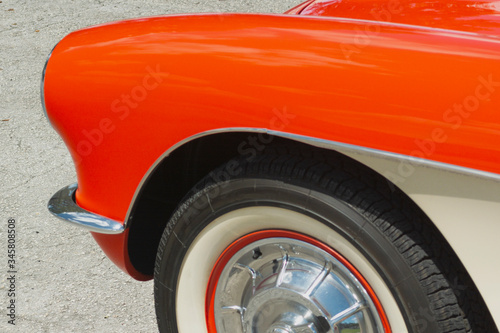 Vintage car of the 50s. Front of a classic American car. Antiquity in colors. Orange classic car. Headlights, chrome, wheels.