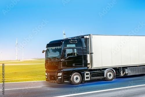 Truck moves on the road at speed, delivery of goods. Truck at dawn sun, flashes down the road