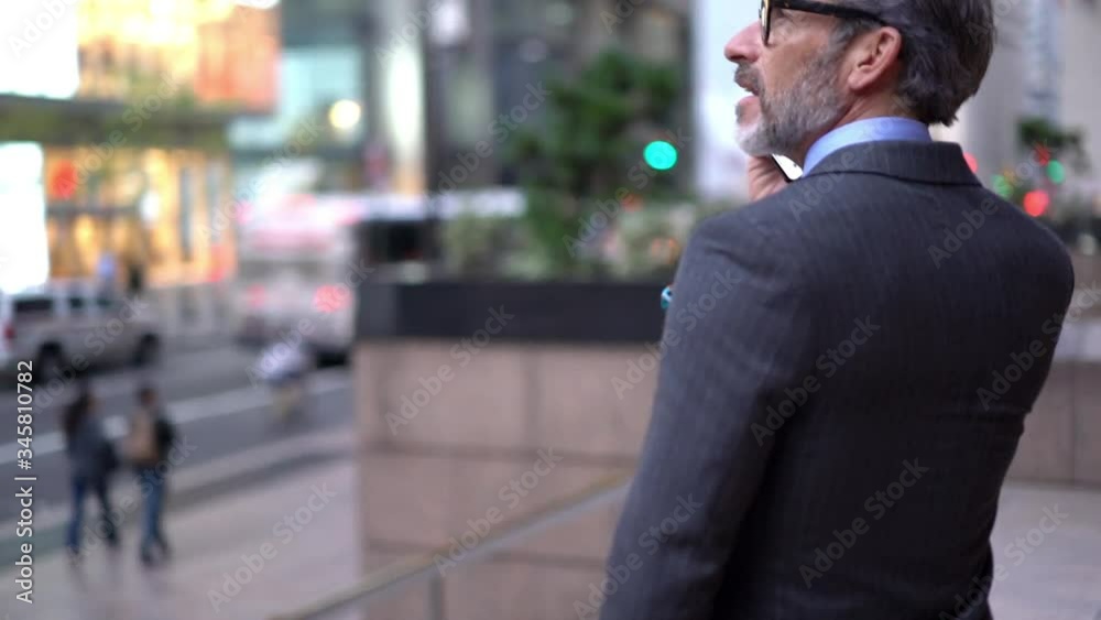 Slow motion effect of middle aged male lawyer in optical glasses making international smartphone conversation for talking with customer and give online consultancy, mature entrepreneur phoning
