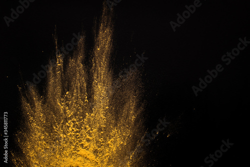 Cloud of yellow paint scattered on black background