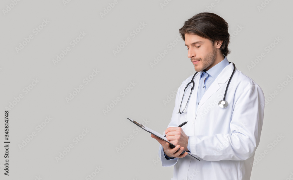 Young doctor reviewing patient's medical history and taking notes to clipboard Young doctor reviewing patient's medical history and taking notes to clipboard