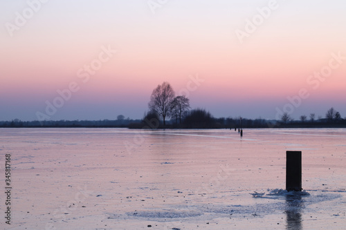A wooden  in a frozen lake during sunset