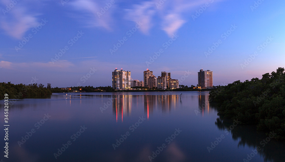 Αυτοκόλλητο Night falls after sunset over Clam Pass as the lights of the highrise buildings