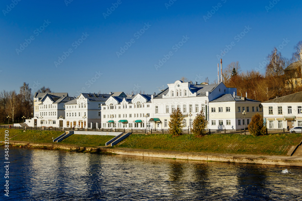 Old buildings by the river. Reflection of white houses in the water.