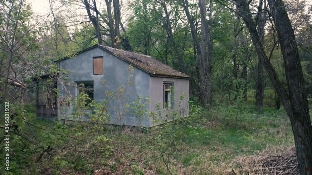 Abandoned haunted house (Rambler house) with cement rendering in a spring dense forest. Aerial low angle shot. Abandoned haunted house (Rambler house) with cement rendering in a spring dense forest. Aerial low angle shot.