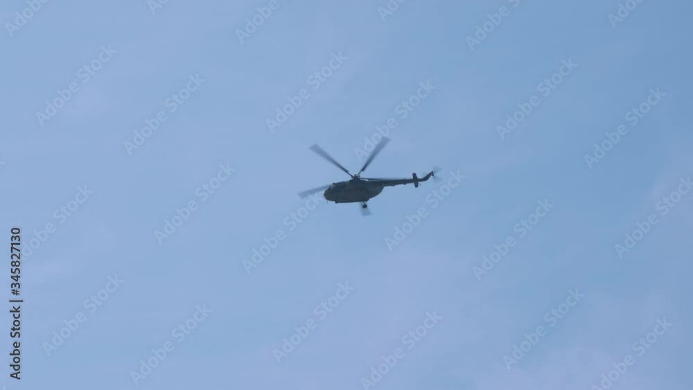 Military helicopter flying against bright blue sky Military helicopter flying against bright blue sky
