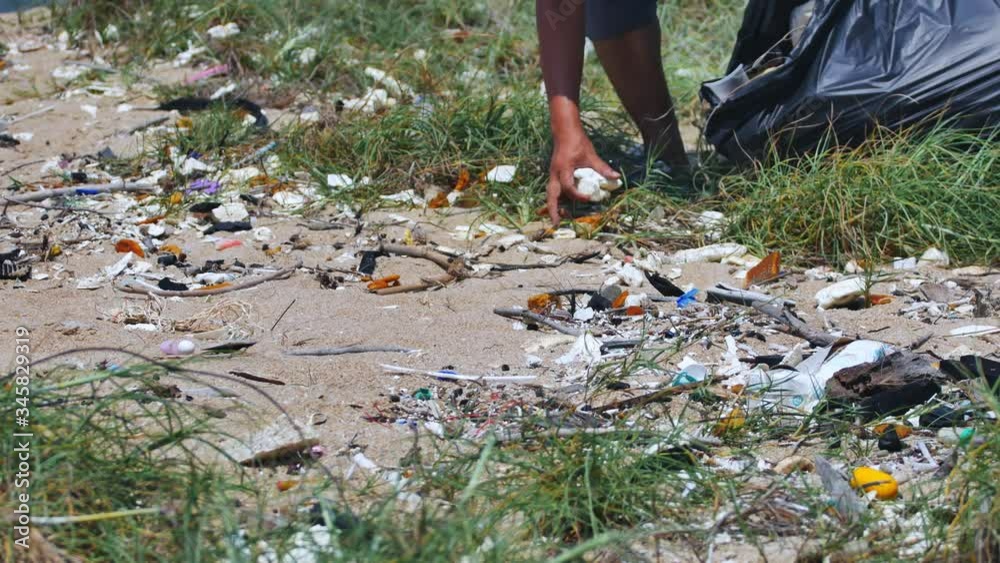 A man cleaning up white beach to keeping plastic garbage into the bag. Recycling and Environmental awareness concept A man cleaning up white beach to keeping plastic garbage into the bag. Recycling and Environmental awareness concept