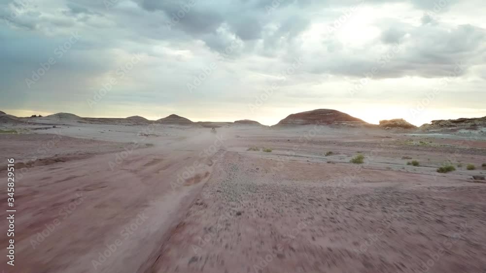 Speedy Tracking Aerial View of Person Driving ATV Vehicle in Dusty Road in Dry Desert Landscape Under Dramatic Sky Speedy Tracking Aerial View of Person Driving ATV Vehicle in Dusty Road in Dry Desert Landscape Under Dramatic Sky