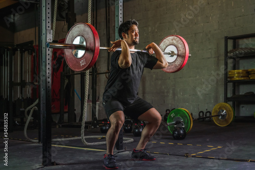 asian strong athletic man having workout and bodybuilding with barbells weight front squat setting style in gym and fitness club in dark tone