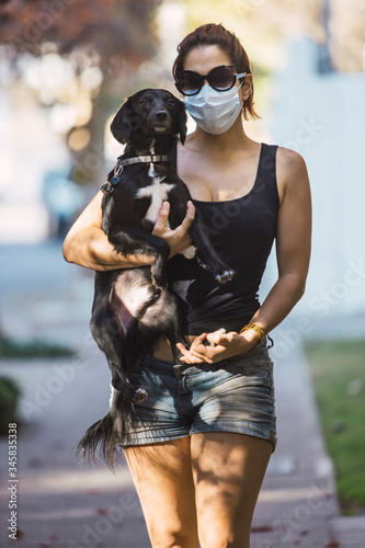 Young woman walking her dogs to exercise and relieve themselves during quarantine caused by the coronavirus pandemic © Rafael