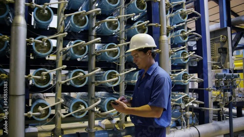 DS TS MS Worker with handheld device walking in water treatment plant
