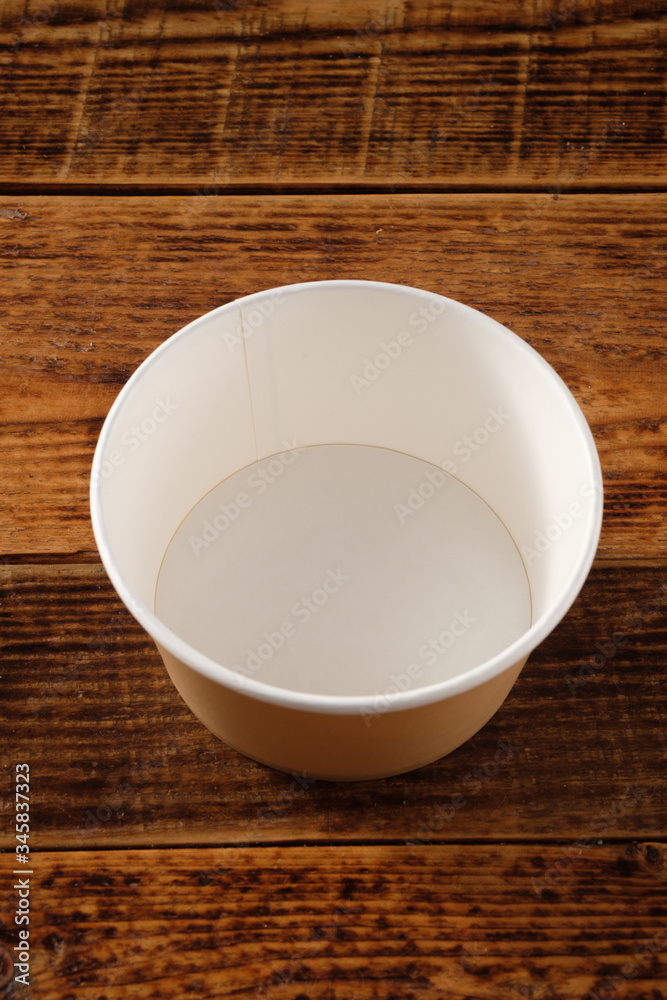 Big brown paper plate isolated on wooden background. Eco-friendly disposable food packaging. Preserving nature and recycling concept. Big brown paper plate isolated on wooden background. Eco-friendly disposable food packaging. Preserving nature and recycling concept.