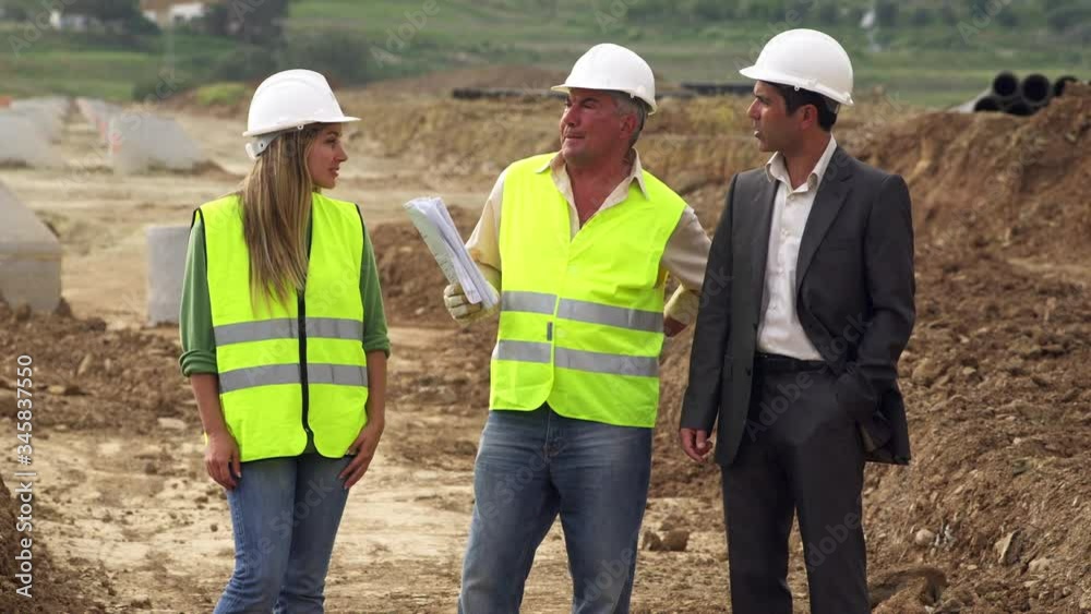 MS Male and female engineers and businessman talking at construction site MS Male and female engineers and businessman talking at construction site