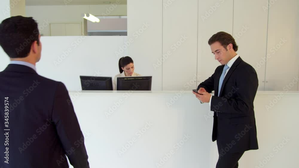 WS Two businessmen at reception area in office WS Two businessmen at reception area in office