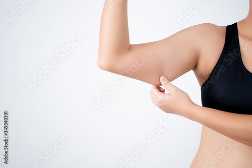 Fototapeta Young woman wearing a black workout outfit is pulling under her arm because she has fat under her arm