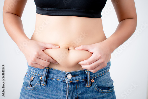 Woman holding excess fat on her belly on a white background