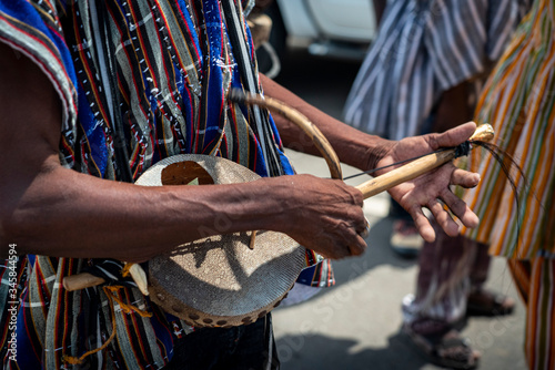 A street musician plays a traditional African Lute also known as a Pluriarc as he marches in a festival celebration parade in Ghana, West Africa.