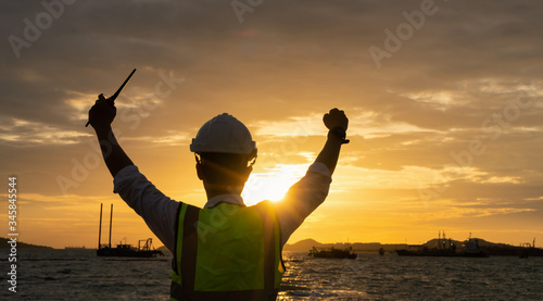 Silhouette of an engineer holding radio communications by the sea at sunset. Engineer Concept..