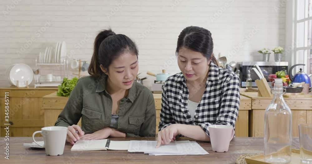 slow motion of happy positive young girl roommates reading document with home finance. smiling female friends discuss budget in modern kitchen. joyful ladies satisfied with money refund in apartment slow motion of happy positive young girl roommates reading document with home finance. smiling female friends discuss budget in modern kitchen. joyful ladies satisfied with money refund in apartment