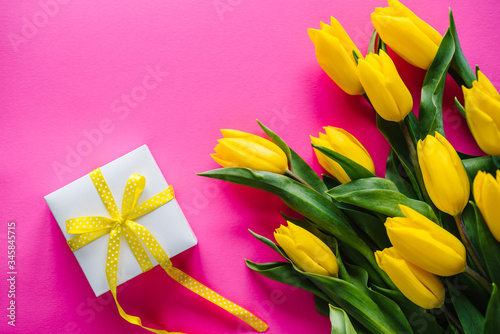 Bouquet of yellow tulips with gift box on pink background. Space for message. Flowers concept. Spring. Holiday greeting card for Valentine s  Women s  Mother s Day  Easter. Birthday. Top view.