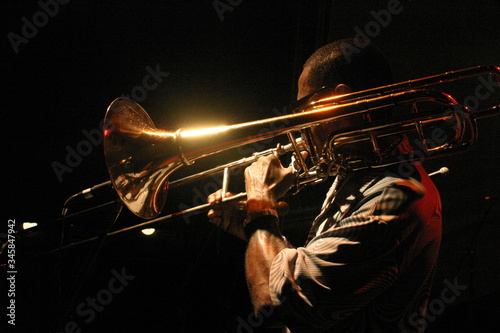 Photography Black man playing shiny trumpet with black background