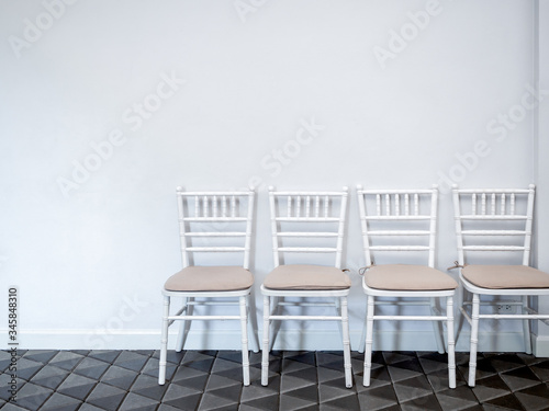 Row of white vintage wooden chairs with pads.