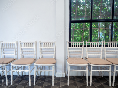 Row of white vintage wooden chairs with pads.