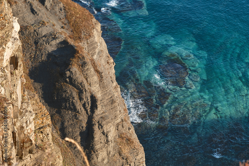 top view from the edge of the cliff to a massive rock and turquoise sea
