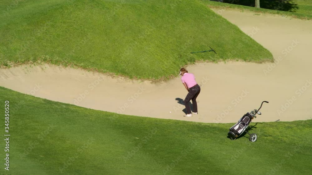 WS Mature female golfer hitting ball out of sand trap WS Mature female golfer hitting ball out of sand trap