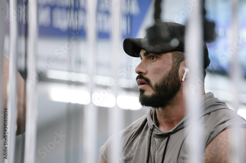 handsome face of strong young bearded man in cap and sleeveless hoodie in sport gym © ruslanshug