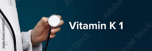 Vitamin K 1. Doctor in smock holds stethoscope. The term Vitamin K 1 is next to it. Symbol of medicine, illness, health photo