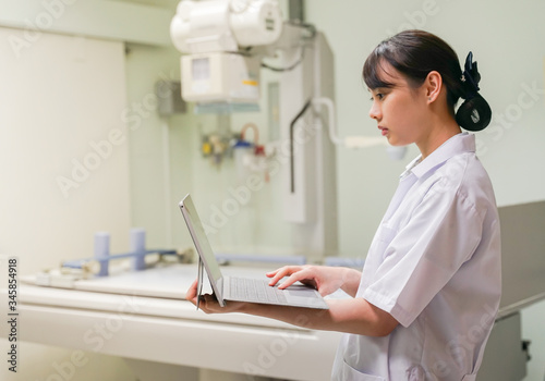 Female Radiologist hold computer laptop prepare for case procedure in Fluoroscopy room, Medical concept © pangoasis