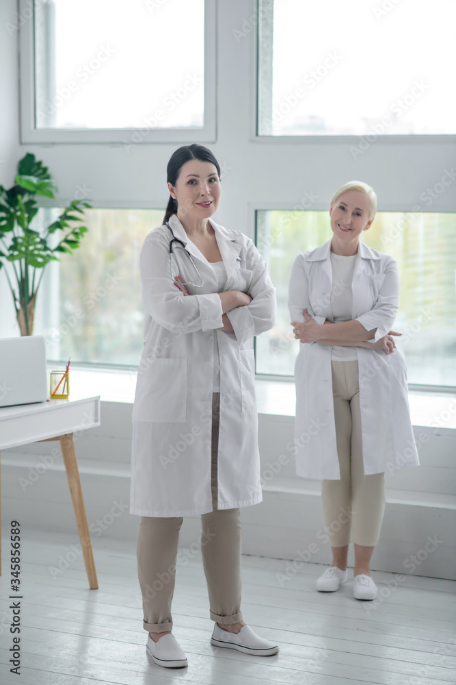 Two doctors in white robes standing in the room Two doctors in white robes standing in the room