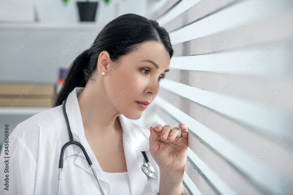 Successful woman in white medical coat near the window. Successful woman in white medical coat near the window.