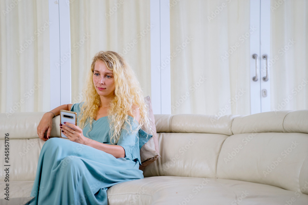 Woman sitting on sofa while using cellphone Woman sitting on sofa while using cellphone