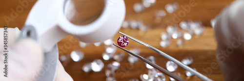 Fotografia Close-up of jeweller hands in gloves looking at gemstones through magnifier