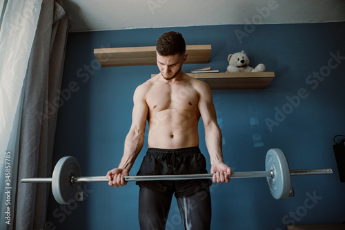 handsome bearded guy exercising with barbell at home