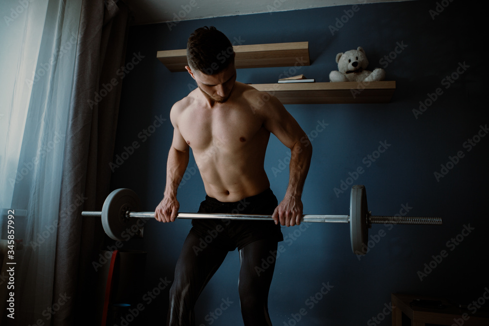 Fototapeta premium handsome bearded guy exercising with barbell at home