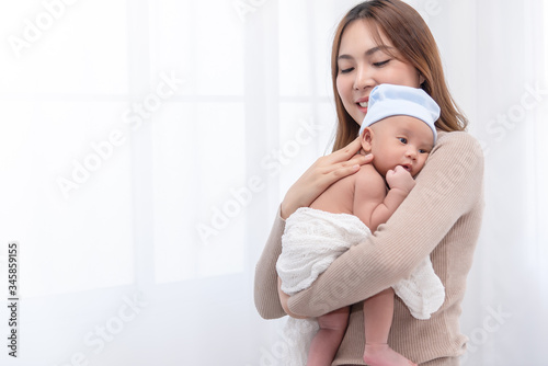 Close up beautiful young asian mother holding her newborn one month baby sleep on her shoulder. Healthcare and medical.  Lovely asian woman lifestyle mother's day concept.