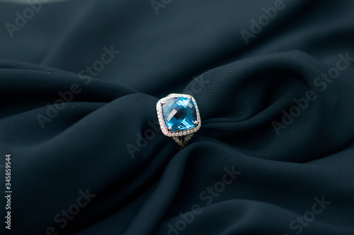 Blue gemstone diamond ring on black fabric. Jewelry product photography. 