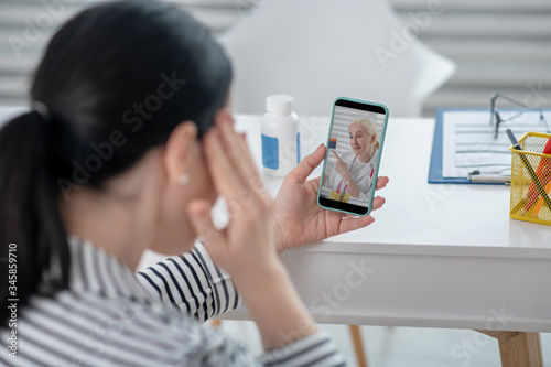 Woman with smartphone hand near head face is not visible.