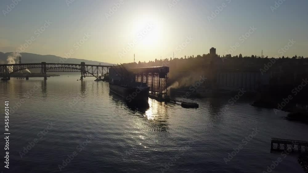A Ship Loading At The Grain Elevator In Burrard Inlet In North Vancouver, Canada With The Ironworkers Memorial Bridge In The Background - Wide Shot A Ship Loading At The Grain Elevator In Burrard Inlet In North Vancouver, Canada With The Ironworkers Memorial Bridge In The Background - Wide Shot