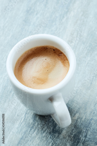 Cup of coffee on bright wooden background.