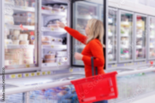 Woman chooses products in the freezing department in a supermarket. Healthy eating and lifestyle. Side view. Blurred. © Анна Демидова